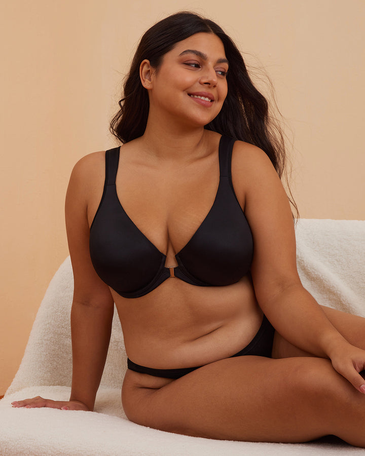 Woman wearing a black bra and underwear set against a beige background