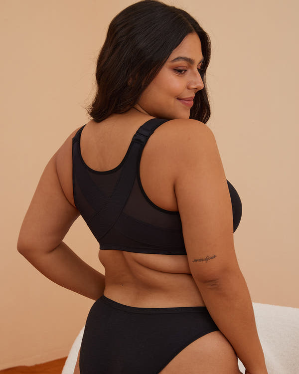 Woman wearing a black bikini against a beige background